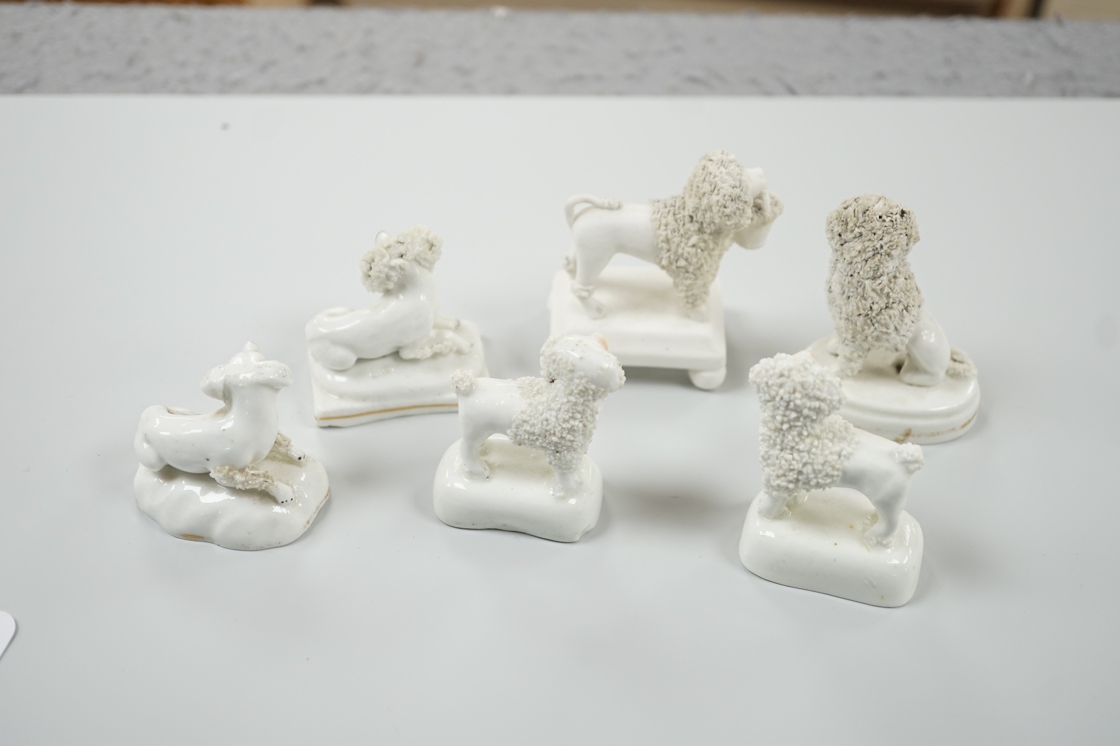 Five small Staffordshire models of poodles, together with a small poodle lying recumbent on an oval mounted base, possibly Davenport, c.1830-50, (6). Tallest 6.8cm., Provence: Dennis G. Rice collection, Cf. Dennis G.Rice